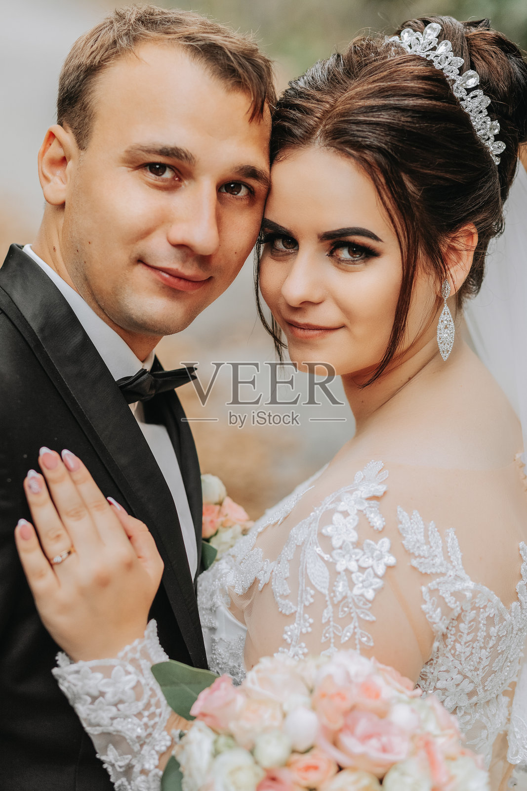 秋天的一天，一对幸福的时髦的新婚夫妇在绿色的公园里。新娘穿白色长裙，新郎穿黑色西装。新郎新娘婚礼当天的特写照片。照片摄影图片