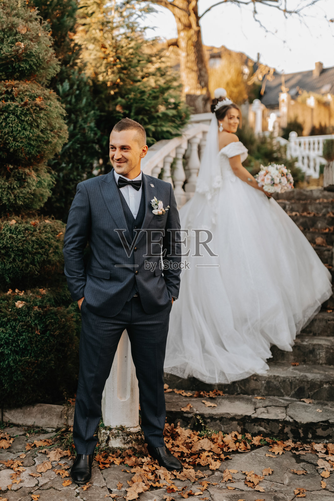 幸福的新婚夫妇的肖像，新娘和新郎在秋天的森林，公园附近的石头台阶摆姿势。一个穿西装的男人，一个穿婚纱的女孩照片摄影图片