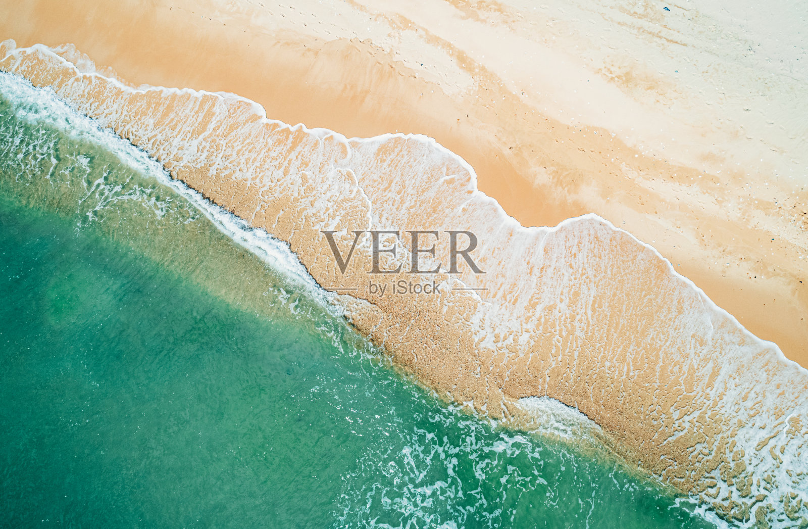 鸟瞰沙滩和蓝绿色海洋。在阳光明媚的日子里海浪到达海岸的俯视图。照片摄影图片