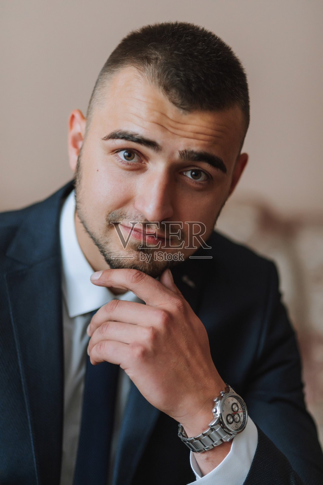 自信优雅的帅哥坐在家里的沙发上，穿着一套漂亮的深蓝色西装。照片摄影图片