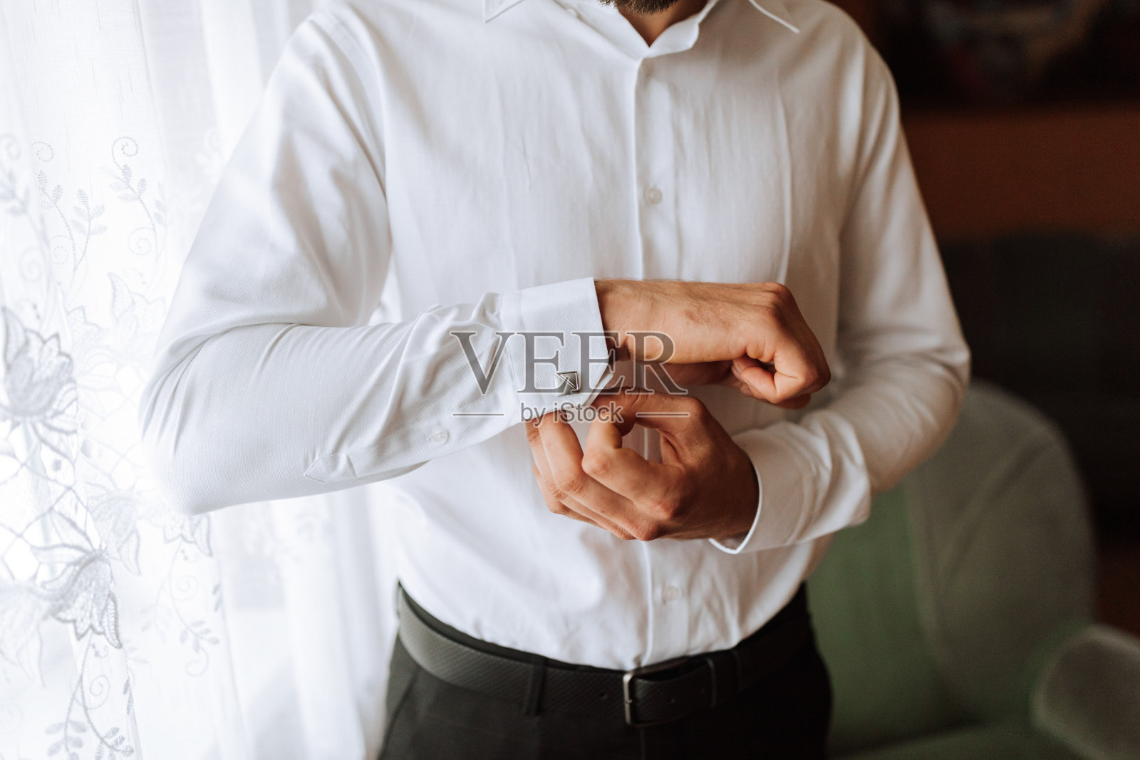 一个男人穿着系扣衬衫的特写。面试服装、工作服装和商务服装。一个男人的手，新郎正在为婚礼做准备照片摄影图片