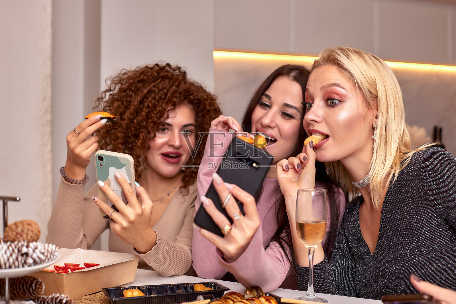 三个漂亮的年轻女子在家里吃日本菜，喝日本酒。照片摄影图片