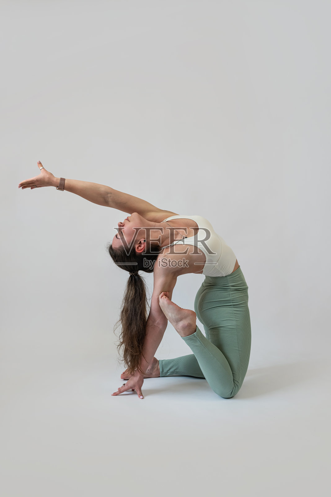 在摄影棚里练普拉提的女人，灰色背景照片摄影图片