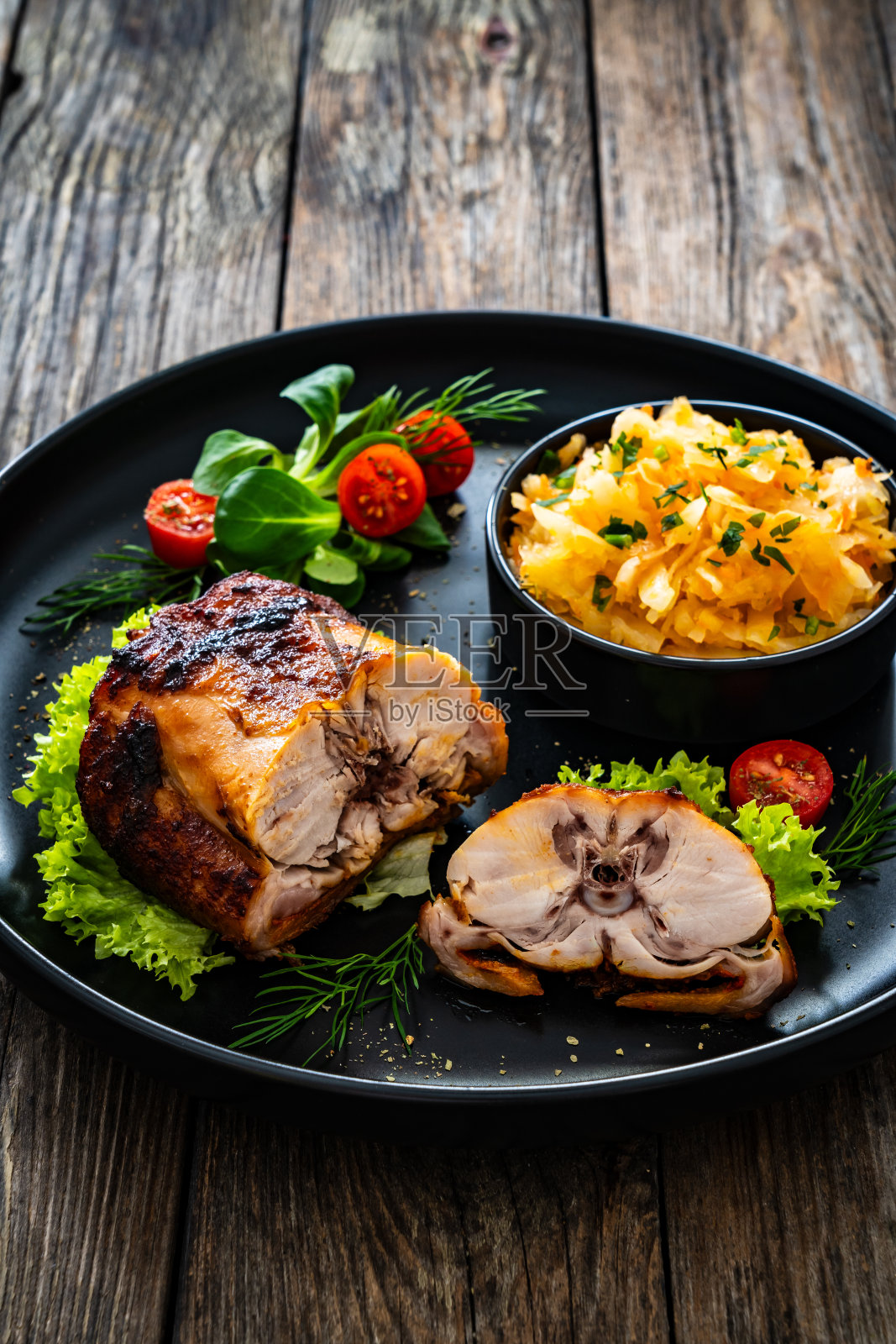 木桌上的烤兔鞍和蔬菜沙拉照片摄影图片