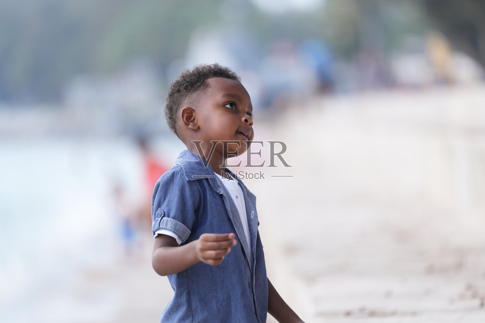 非洲和亚洲混血男孩在户外玩耍。微笑的快乐男孩在沙滩上奔跑。男孩的生活方式与独特的发型的肖像。照片摄影图片