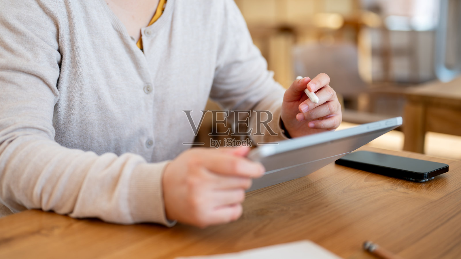 一个女人在室内或极简咖啡馆的桌子上用她的数码平板电脑工作的剪辑照片。照片摄影图片
