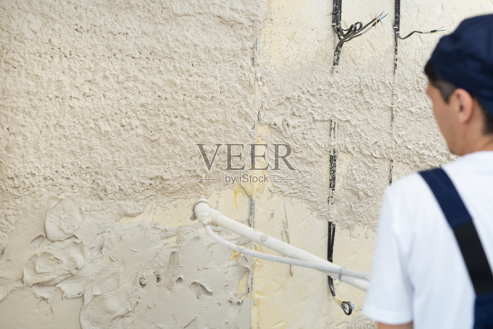 用机器把灰泥涂在建筑物墙壁上的过程。照片摄影图片