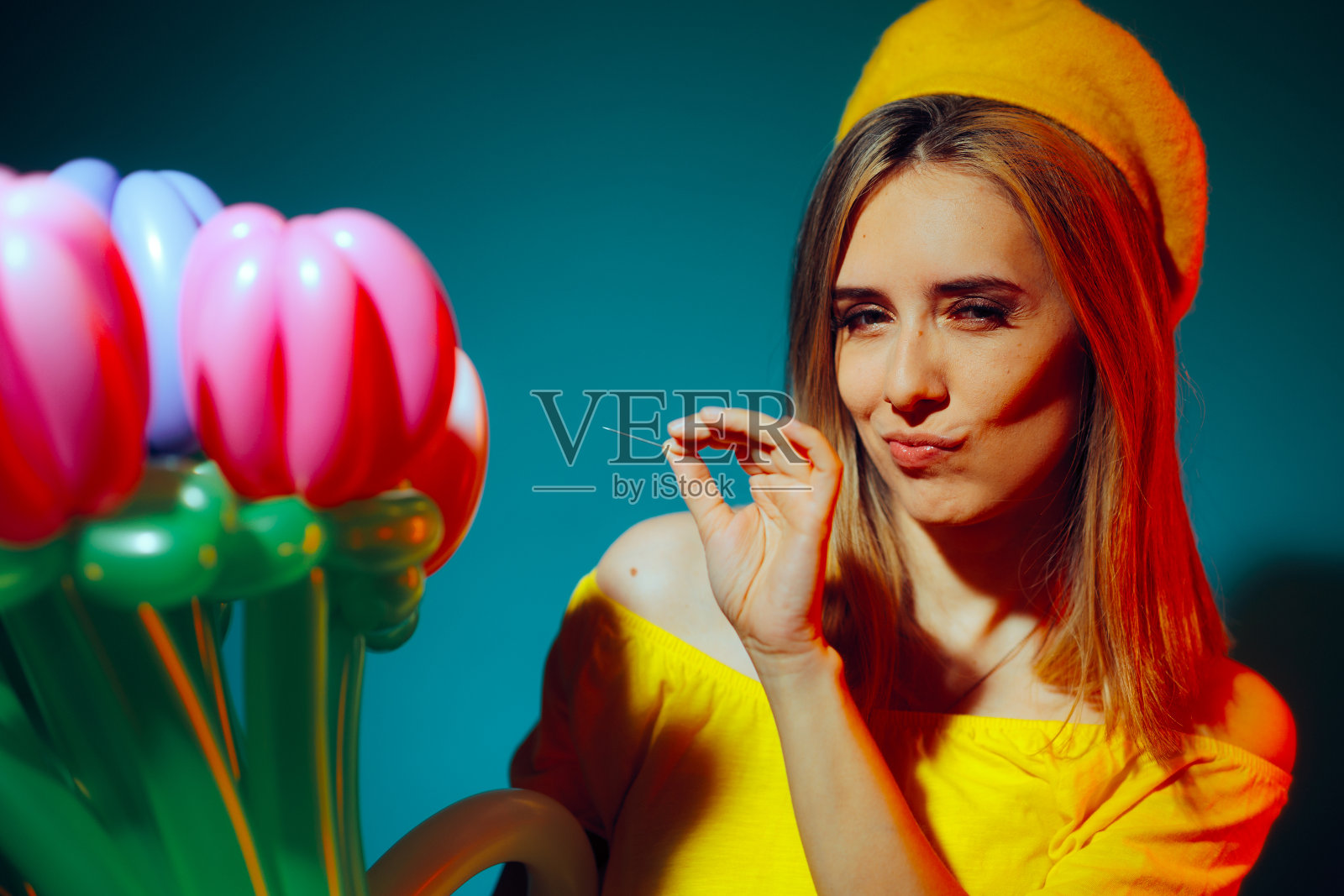 一名女子拿着一根针准备恶作剧地戳破一个气球照片摄影图片