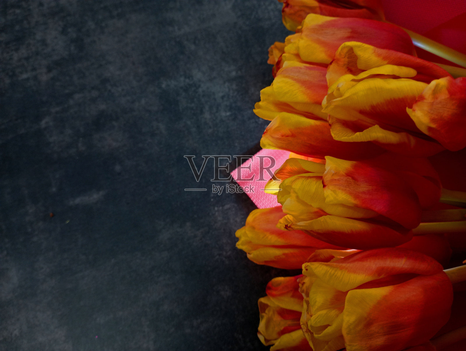 黑色混凝土背景上的一束红玫瑰。背景花。美丽的花朵在角落里黑色的背景。黑色背景上美丽的花束。照片摄影图片