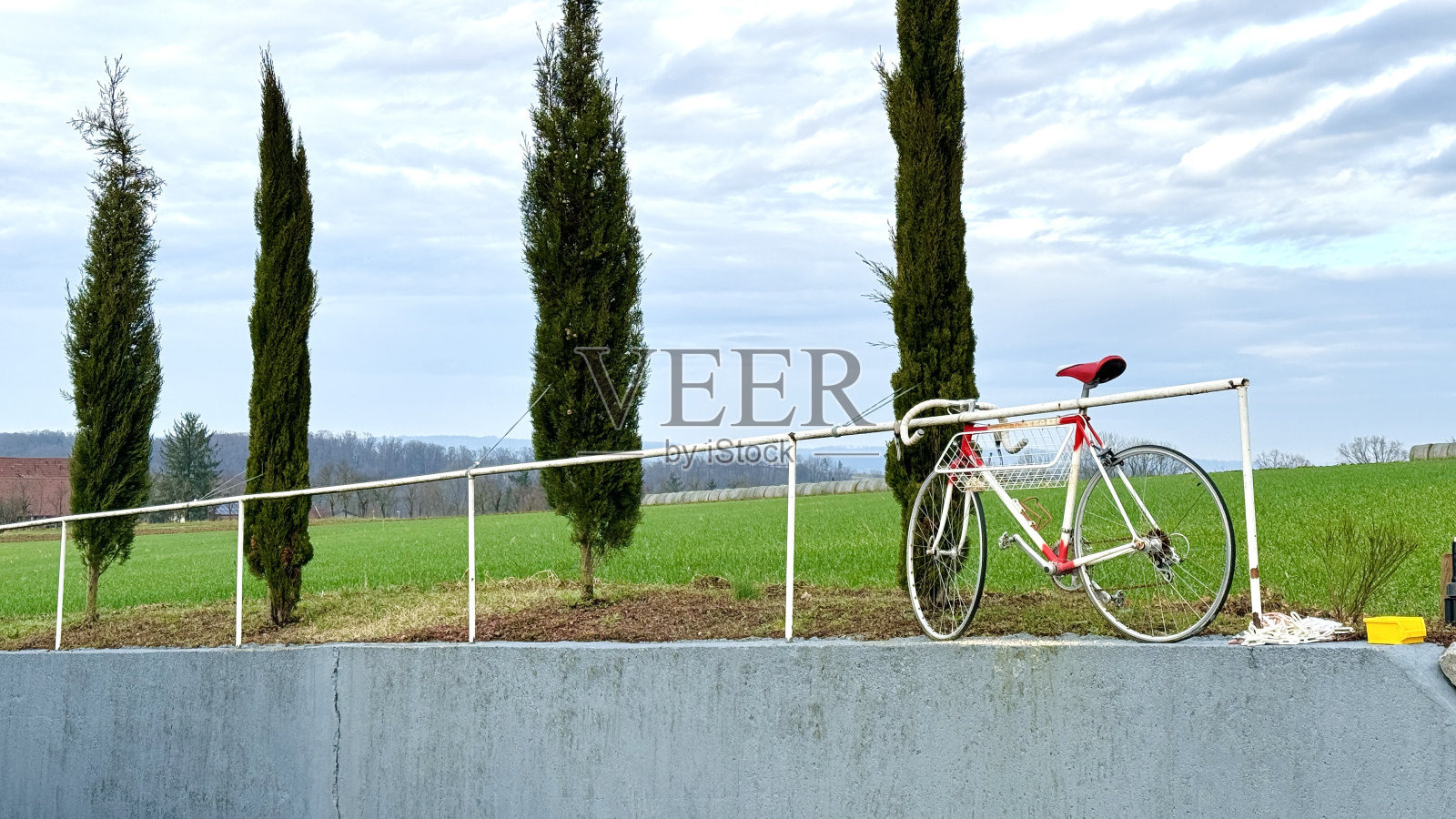 生锈的老式红白赛车在一个旧的白色栏杆杆上丢失了照片摄影图片
