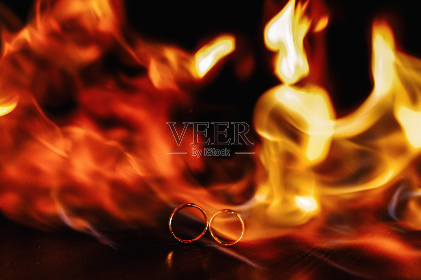 两个结婚戒指在黑暗的背景上的火焰。的婚礼。传统。火相星座照片摄影图片