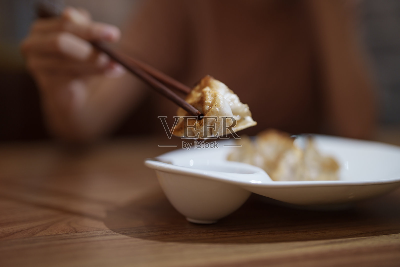 一个女人在餐馆里用筷子吃着刚出炉的煎饺照片摄影图片