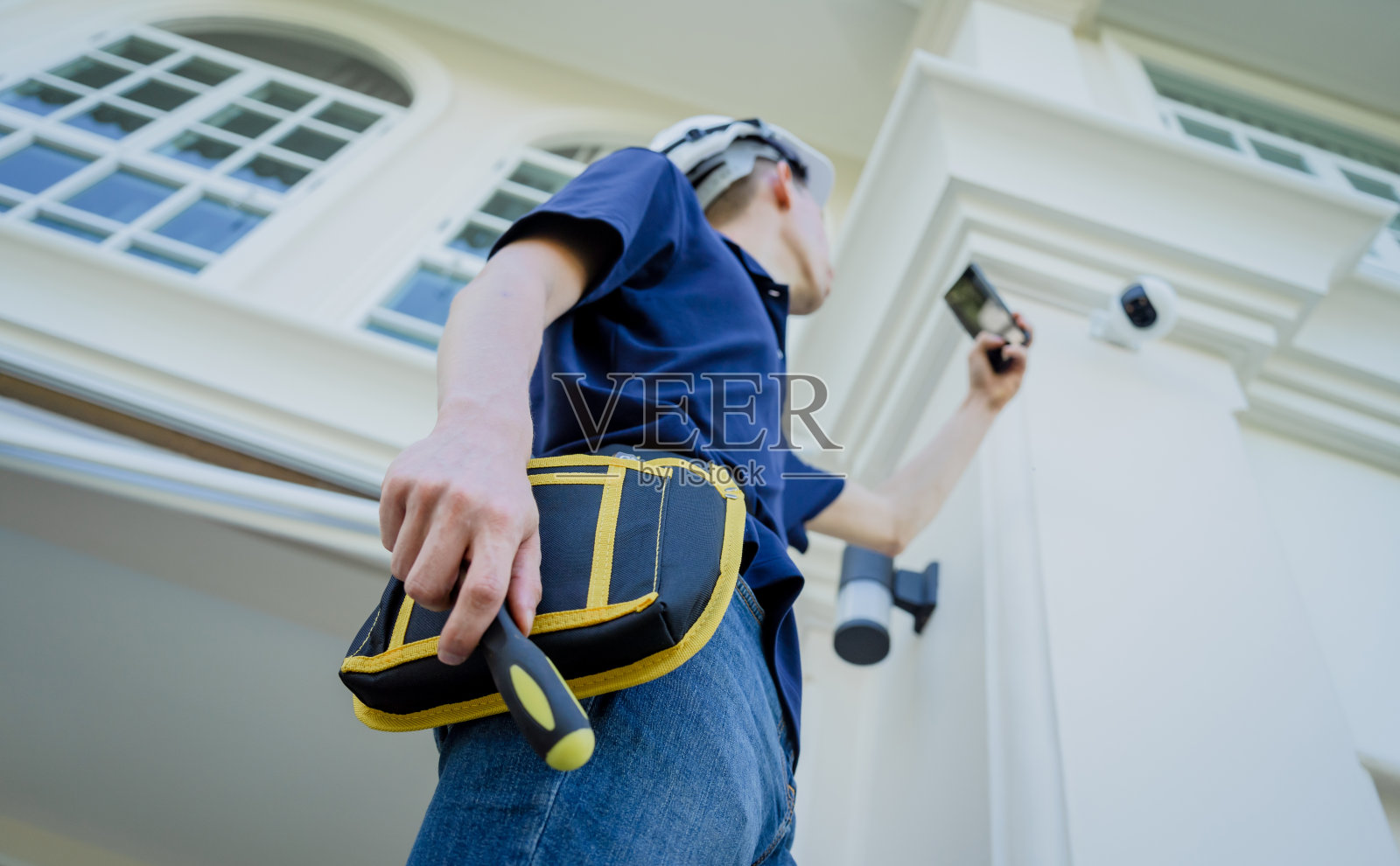 一名技术人员在住宅楼的正面安装闭路电视摄像机。照片摄影图片