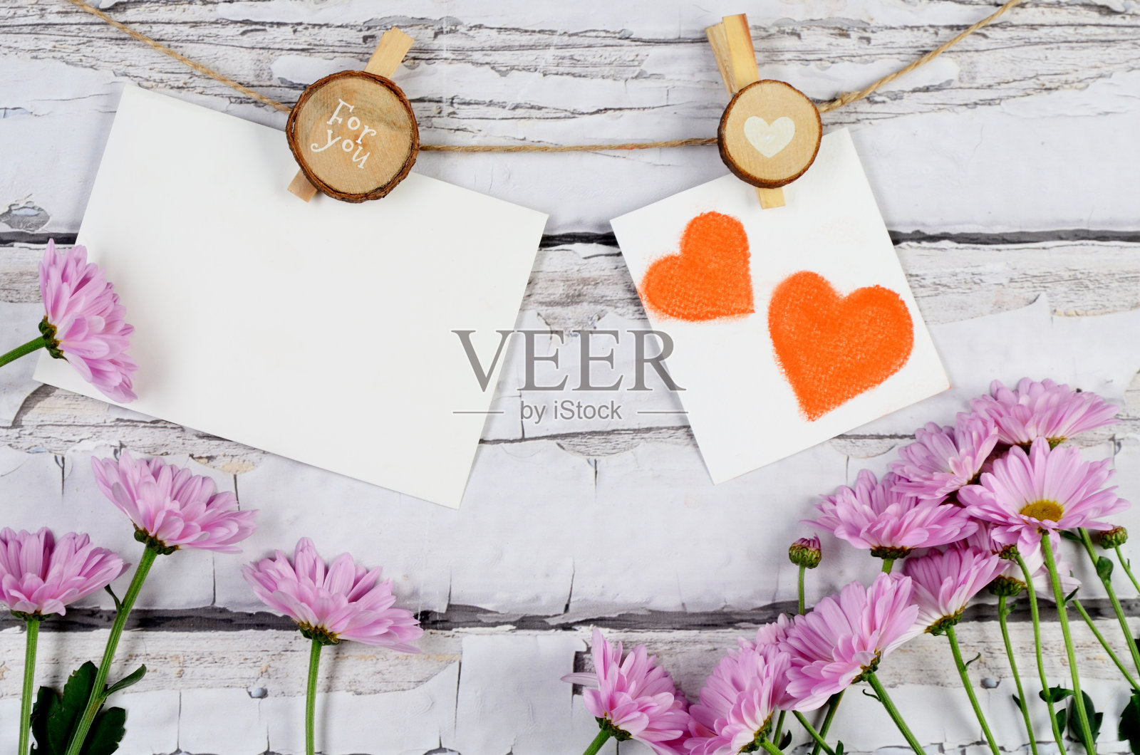 母亲节贺卡：装饰模型、粉色花朵和悬挂在木质背景绳索上的心照片摄影图片