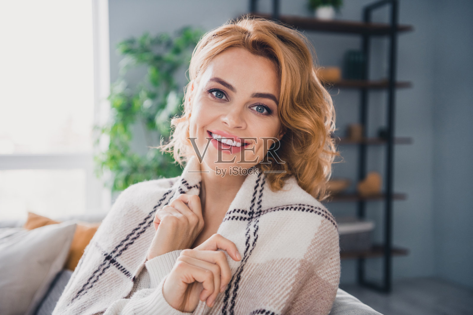 相当满意高兴的人的肖像笑容满面地坐在沙发上盖上自己温暖的毯子明亮的房子里面照片摄影图片