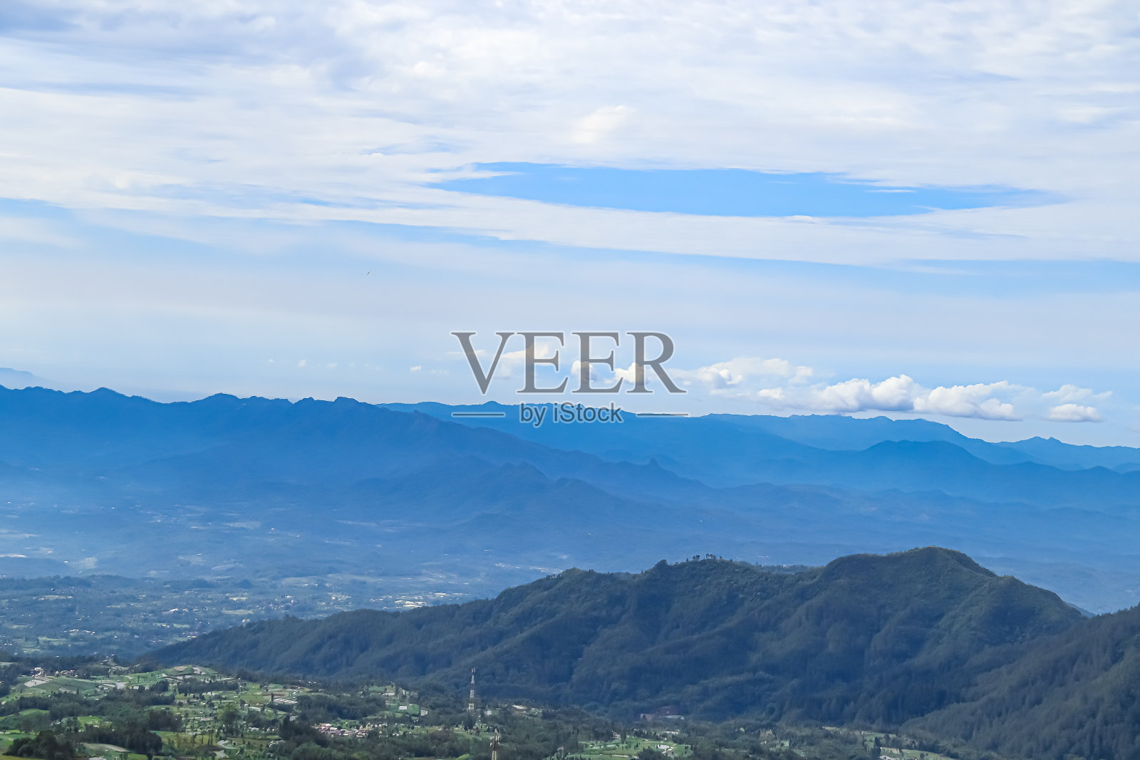 远处翠绿的山景景观，背景是湛蓝的多云天空照片摄影图片