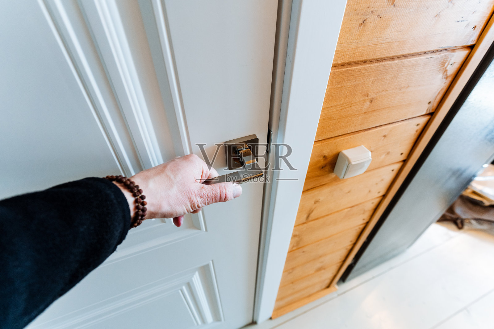 人正在打开一扇白色的门，背景是木制的橱柜照片摄影图片