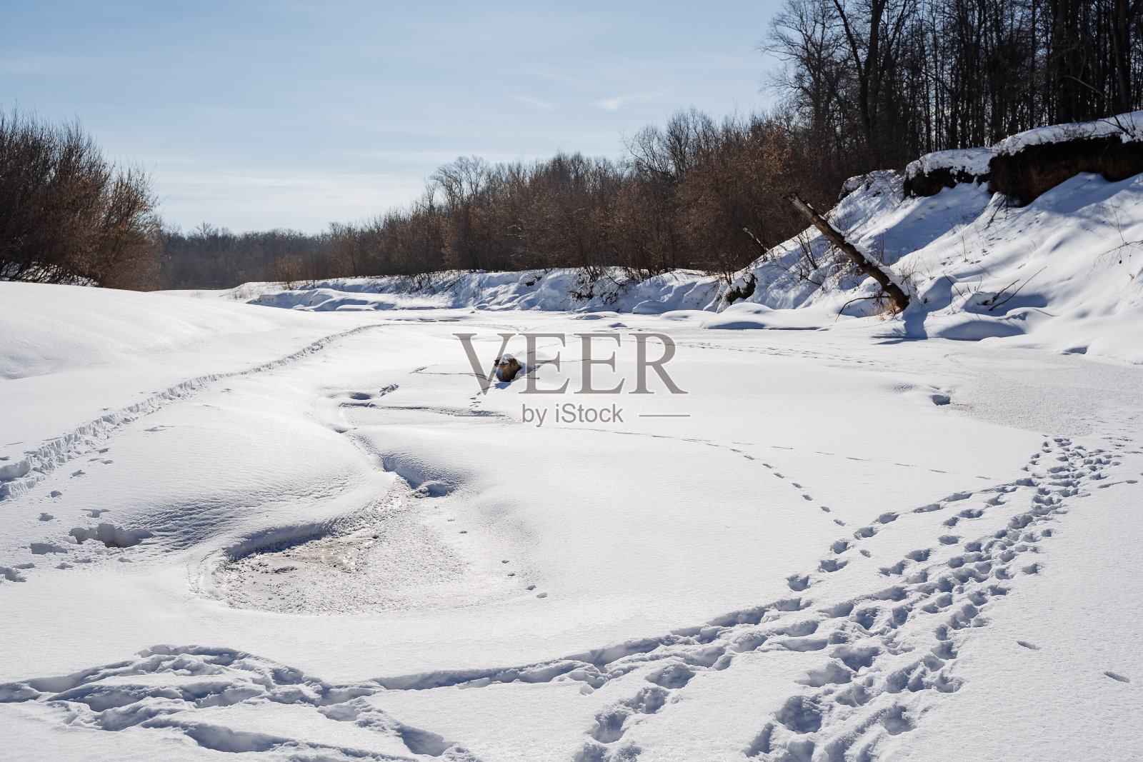 雪白的河上有脚印，有树木，还有阴云密布的天空下冰冷的河水照片摄影图片