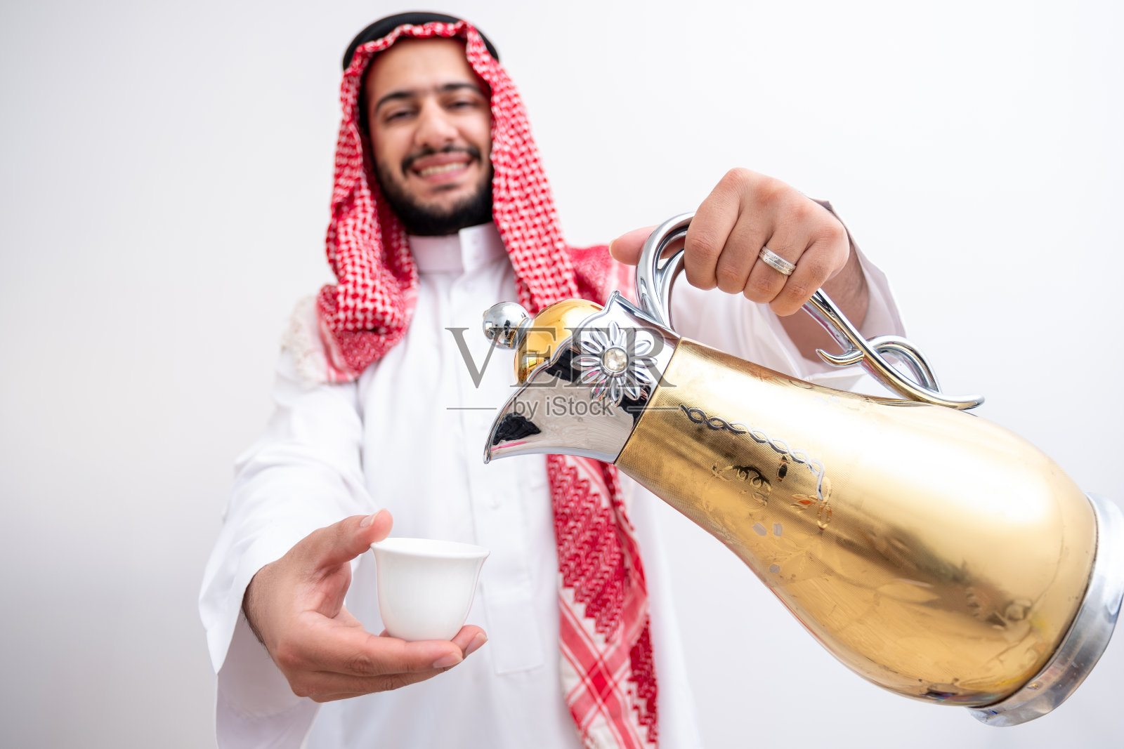 穿着阿拉伯传统服饰，热情好客地端着咖啡 pot 的阿拉伯男人照片摄影图片