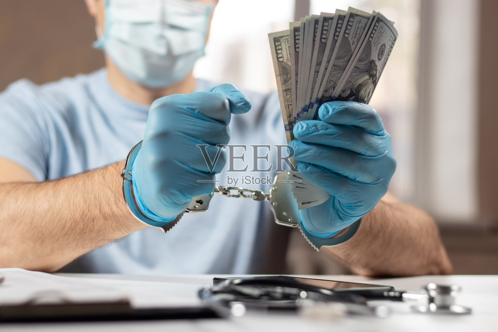 一个带着美元钞票和手铐的医生。医疗腐败、贿赂、犯罪的概念照片摄影图片
