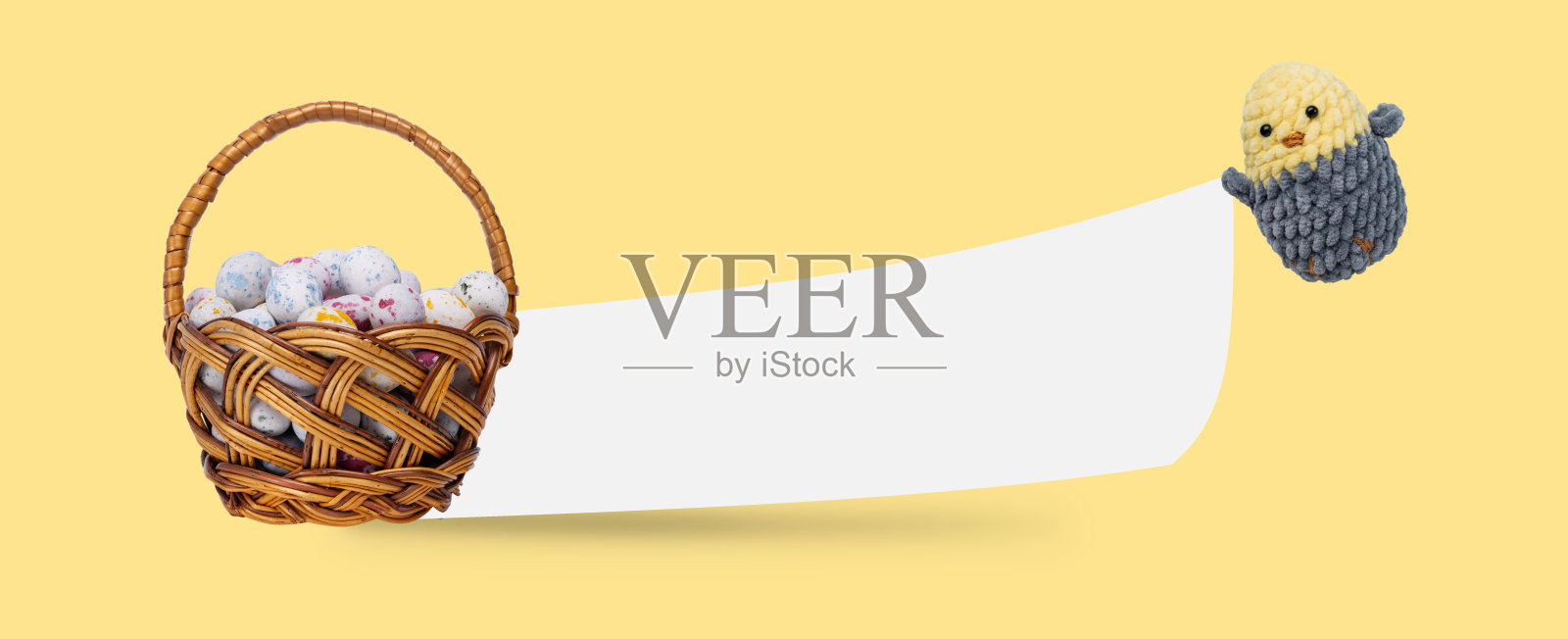 黄色背景的“复活节快乐”明信片。篮子里的复活节彩蛋和一只编织的小鸡，手里拿着复活节的祝福照片摄影图片