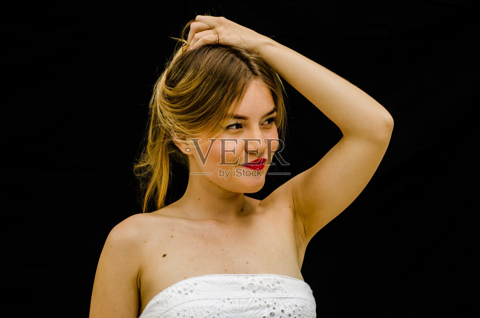 美丽的金发女子在黑色背景下玩弄她的头发照片摄影图片