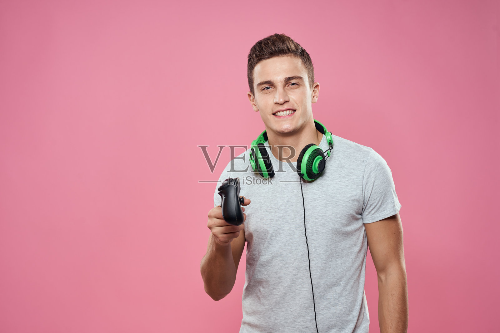 一个人手里拿着操纵杆耳机玩游戏娱乐生活白色t恤粉色背景照片摄影图片