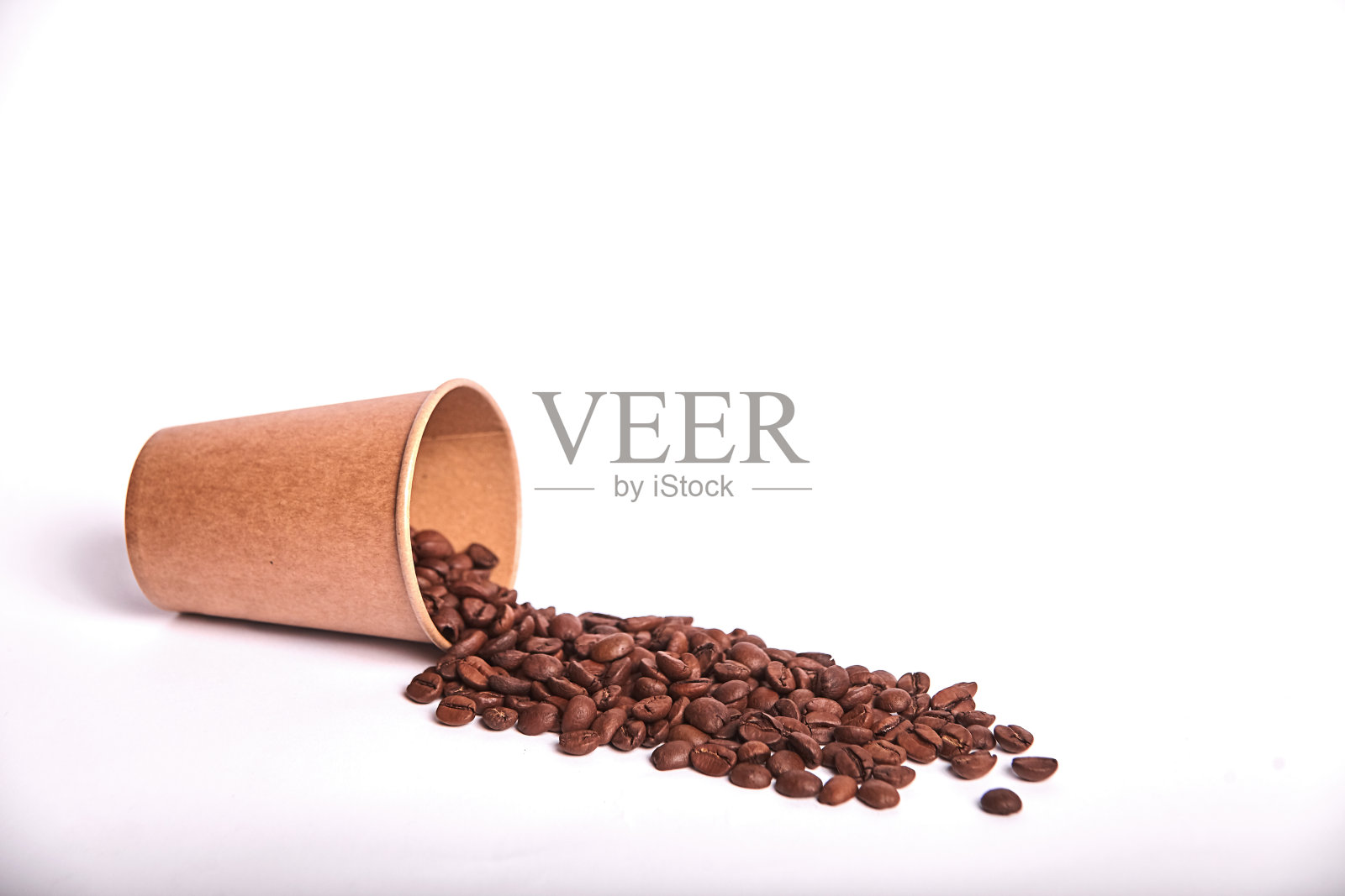 小路上的咖啡豆从工艺玻璃中倒出，咖啡上孤立的白色照片摄影图片