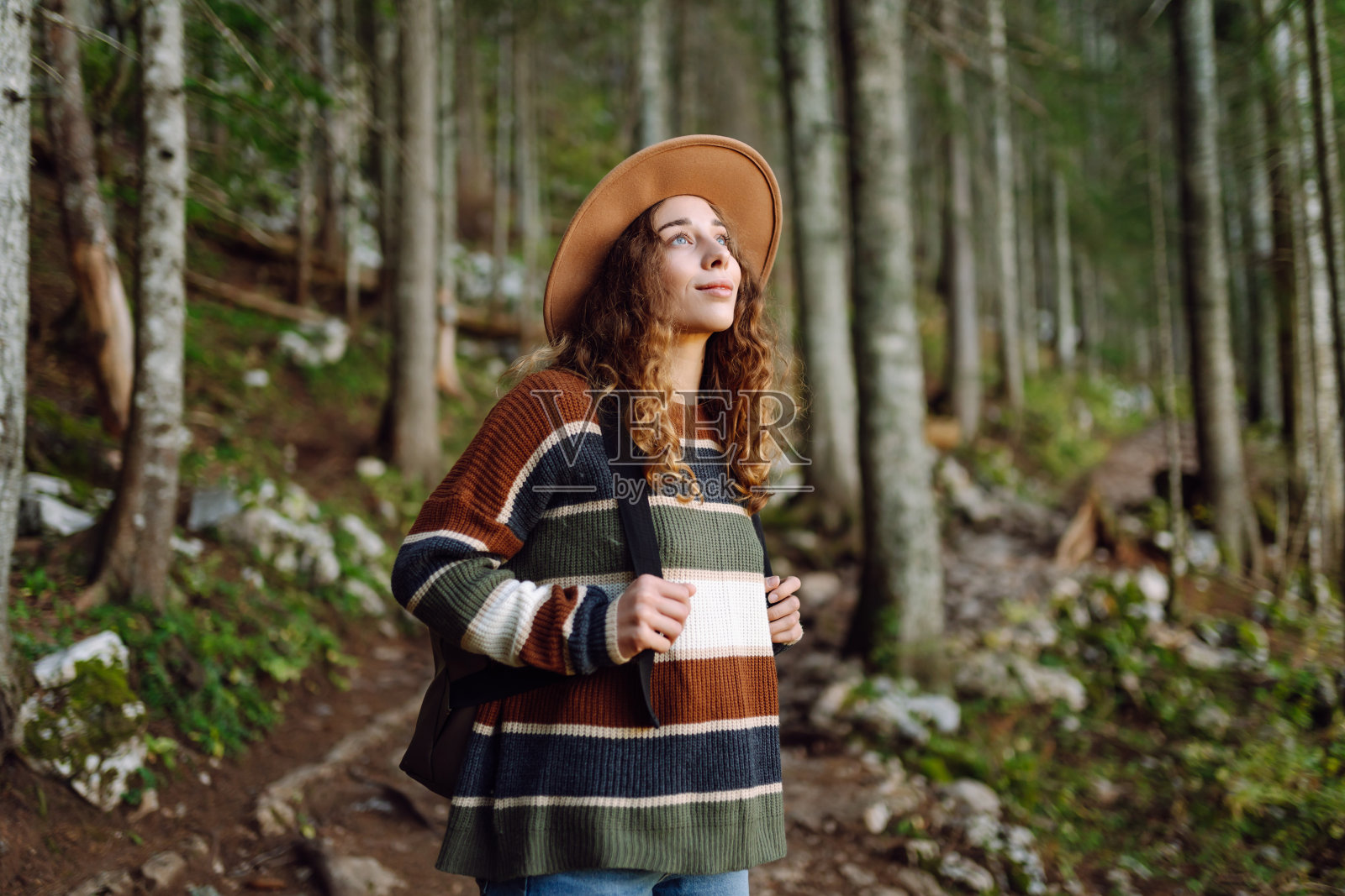 背着背包的年轻女子走在美丽的森林里。照片摄影图片