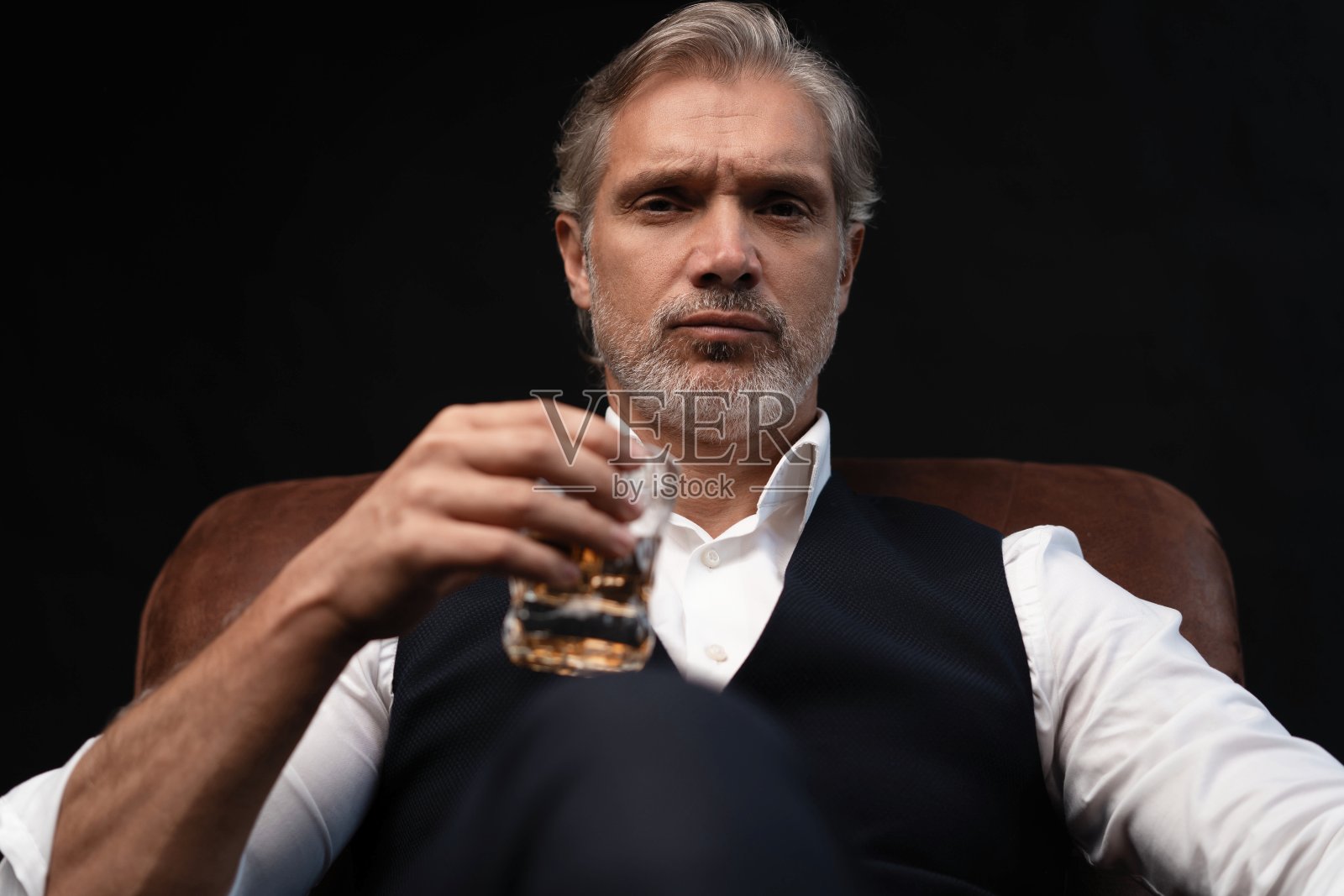 品尝品尝。有胡子的男人端着一杯白兰地。品尝和品尝的概念。留着胡子的商人，穿着优雅的西装，端着一杯威士忌照片摄影图片