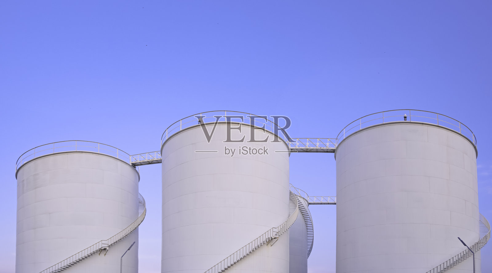 石油工业区的一组白色储油罐，以蓝天为背景，低角度视角与复制空间照片摄影图片