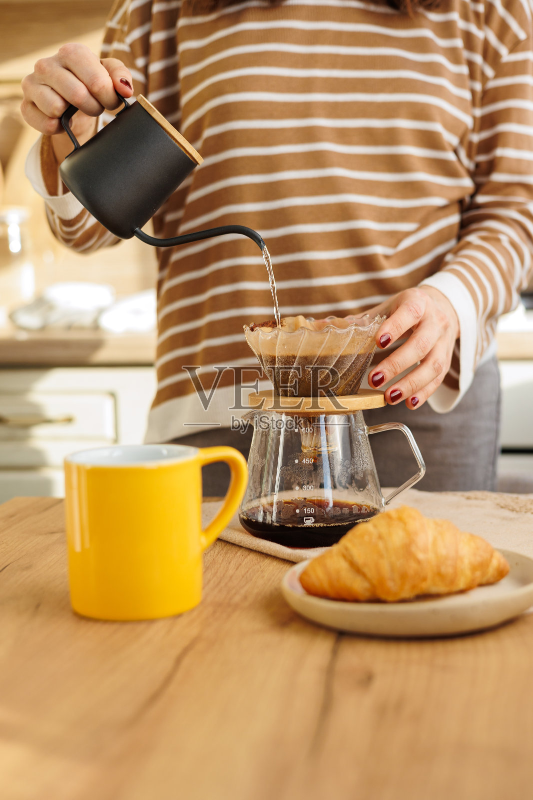 女服务员在厨房煮咖啡。用面粉煮。黄色的杯子上滴着黑咖啡照片摄影图片