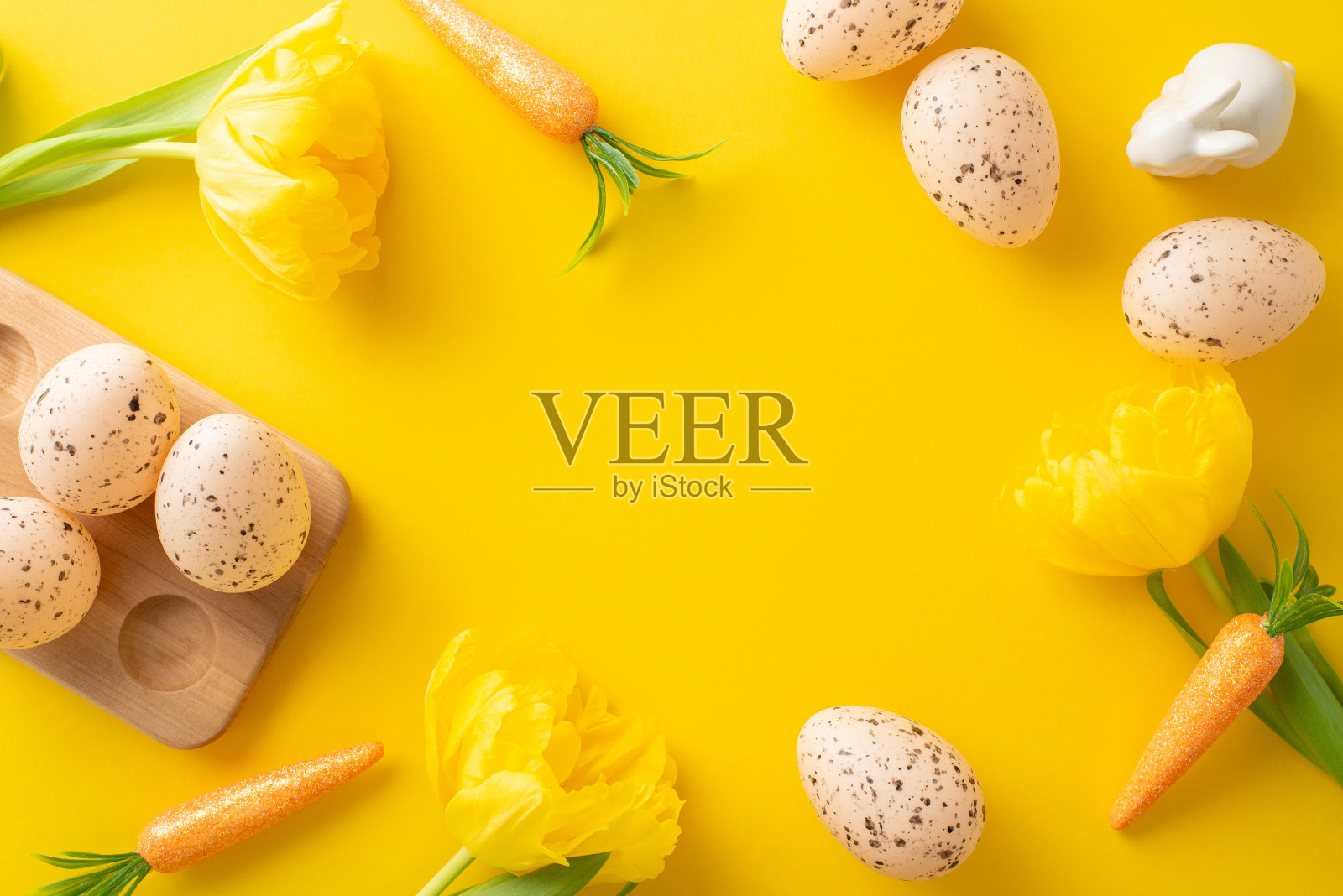 复活节快乐的概念。顶部视图的鸡蛋在一个木制的持有人，兔子的零食，和郁金香在一个辐射黄色的背景与空间为您的内容照片摄影图片