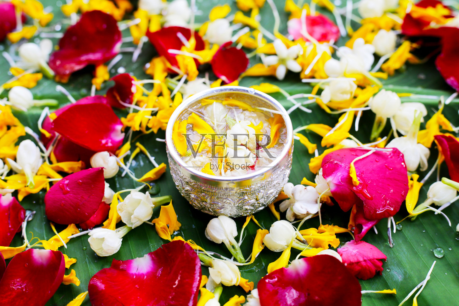 银碗里装着茉莉花、金盏花和玫瑰花瓣。泰国传统，宋干节的概念照片摄影图片