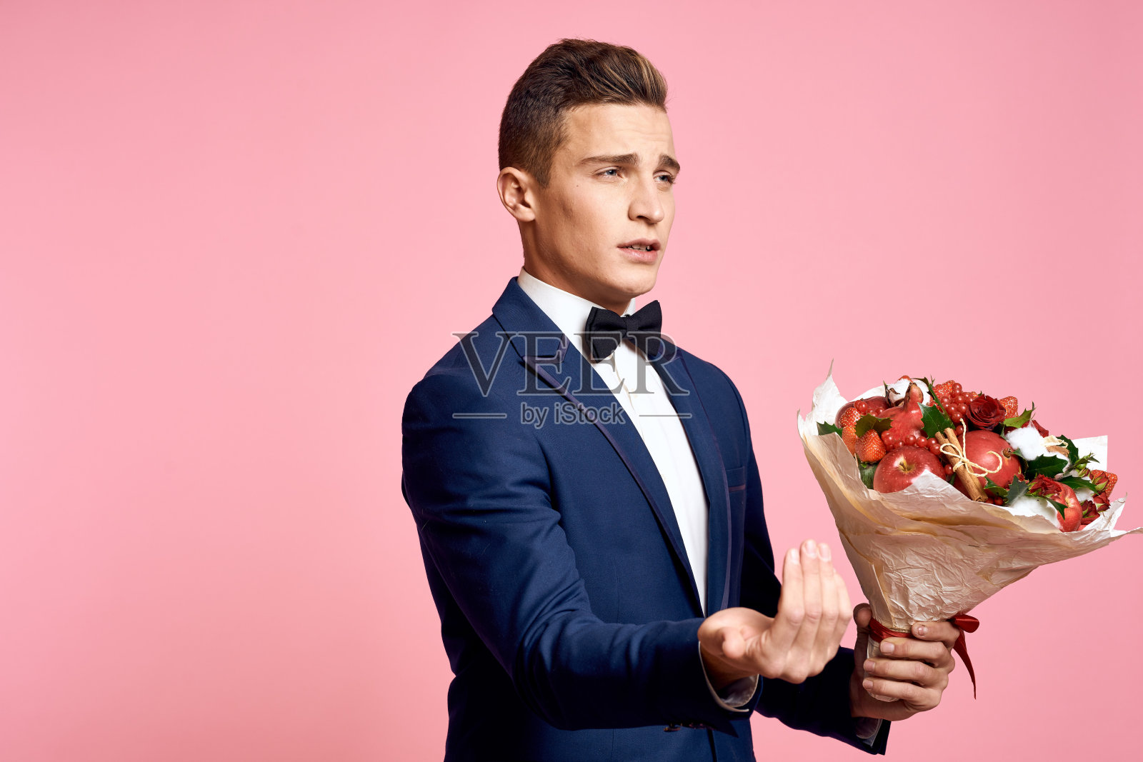 帅哥在经典的西装与一束花在一个粉红色的背景假日领结模型照片摄影图片
