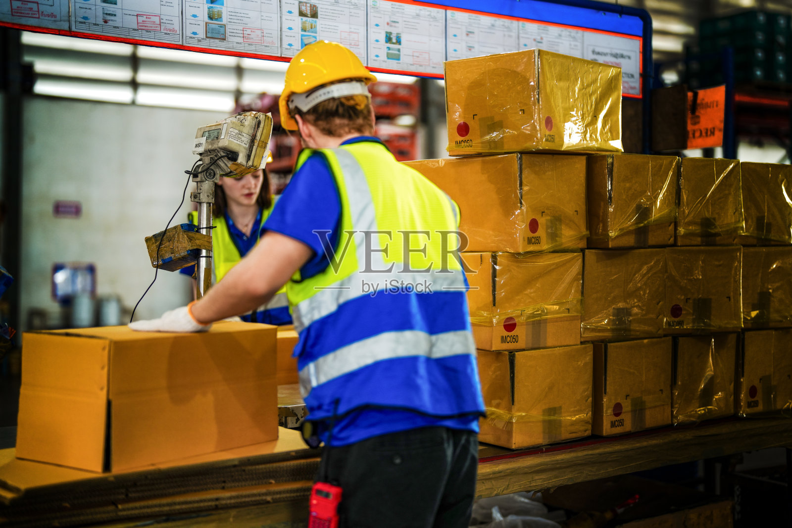 仓库工人在大仓库里折叠纸盒包装物品。在货物库存中密封纸箱的工人。照片摄影图片