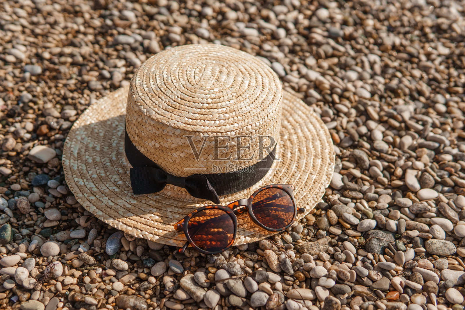 沙滩上的草帽和太阳镜。海边的鹅卵石，特写。自然背景。照片摄影图片