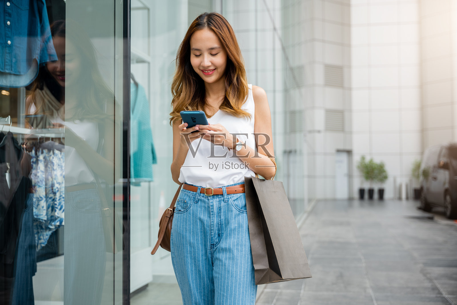 靠在城市墙壁上看手机的女人照片摄影图片