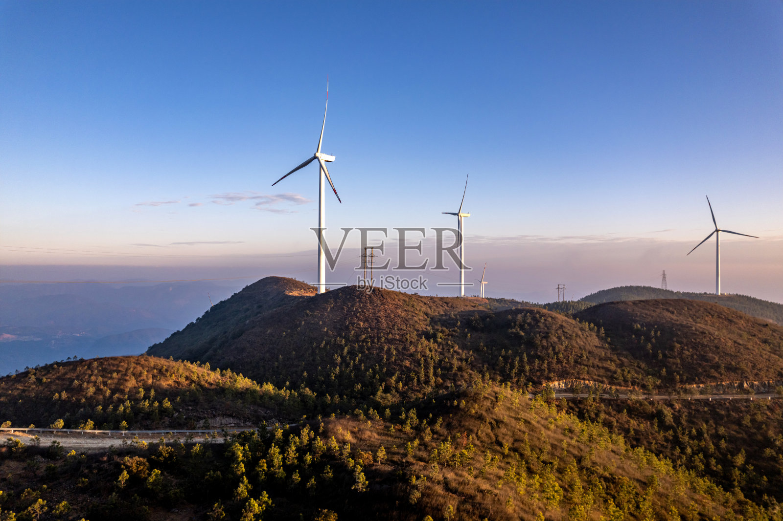 黄昏时分，山上的梯田和风力涡轮机照片摄影图片