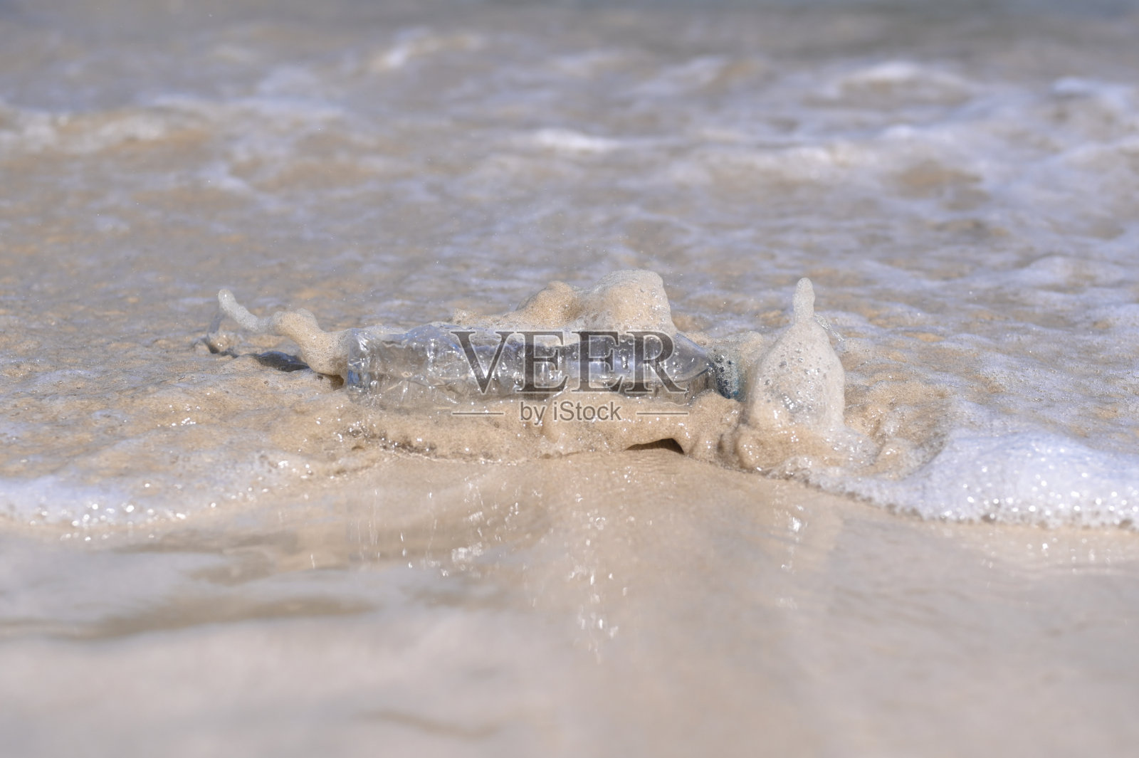 被冲上海滩的矿泉水瓶照片摄影图片