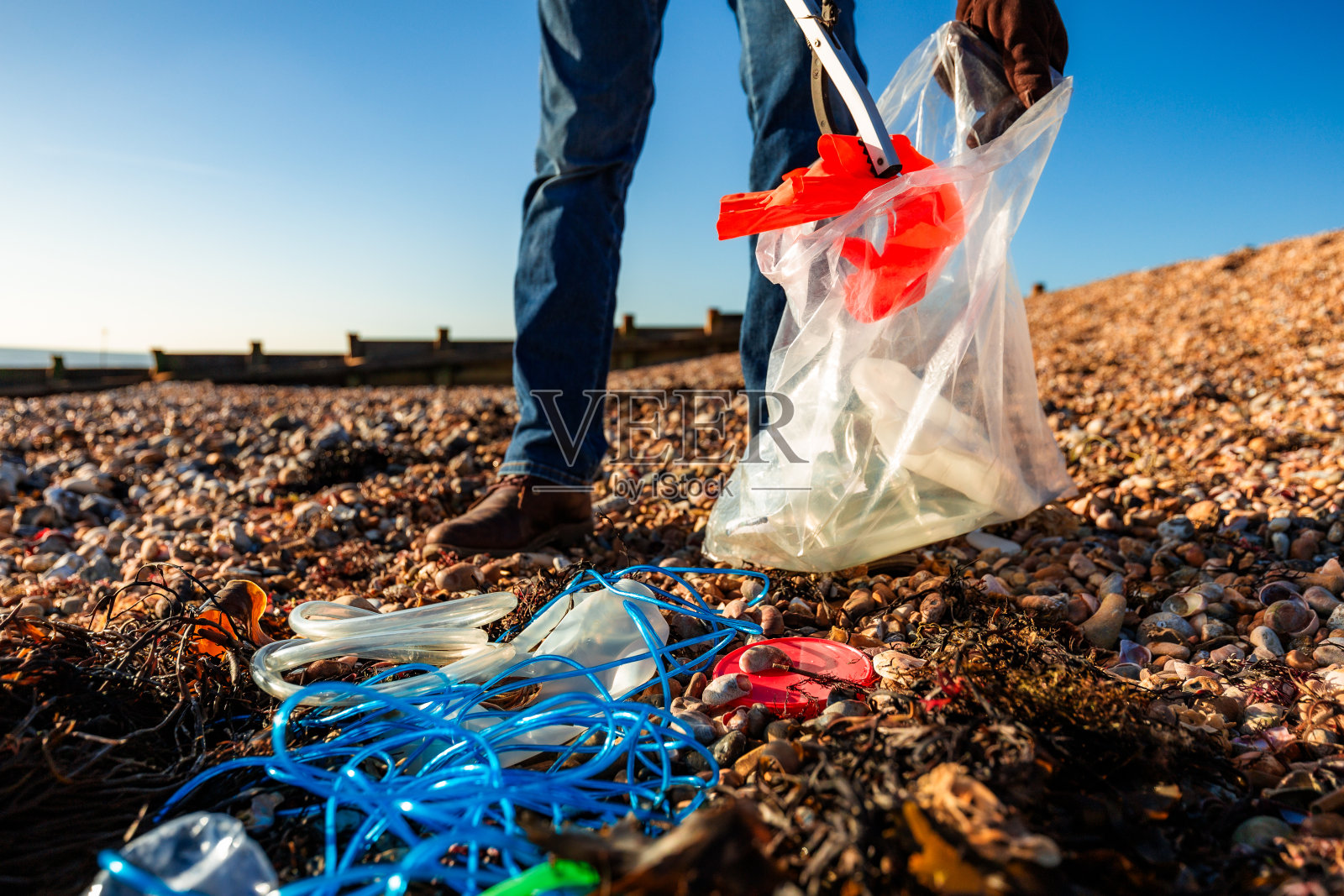 一位老人正在清理海滩上的塑料污染照片摄影图片