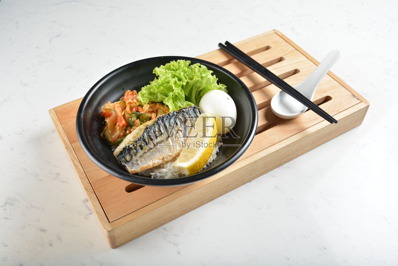 日本烧烤韩国沙巴鱼海鲜柠檬，煮鸡蛋，泡菜和米饭碗黑色碗在白色大理石桌子亚洲咖啡馆健康戳碗清真素食菜单照片摄影图片