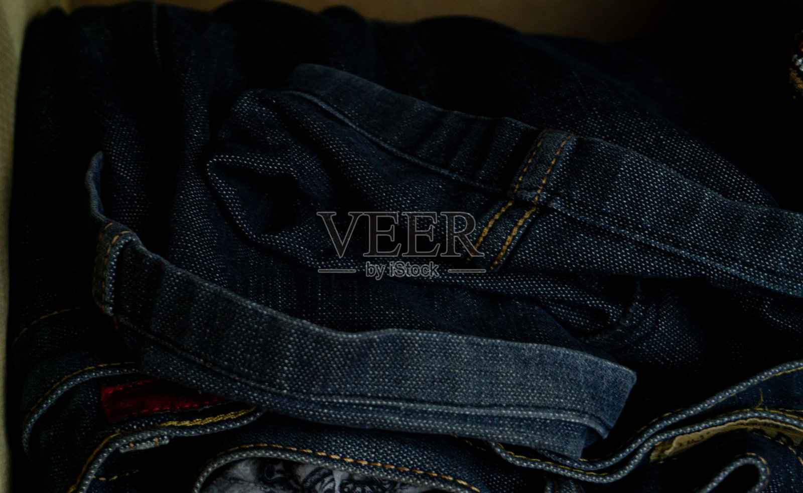 折叠的裤子、胸衣、祈祷垫和纱笼摆放在一个木制橱柜里照片摄影图片