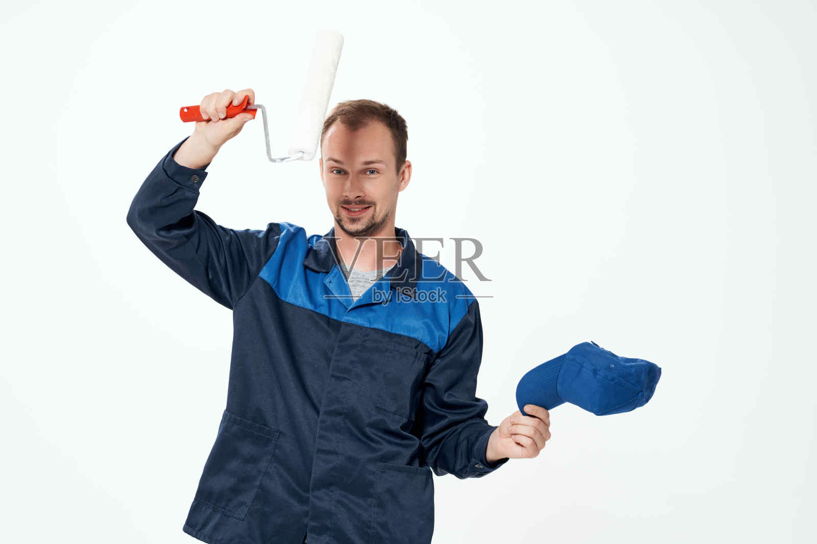 一名身穿工作服的男子，手里拿着刷墙用的滚筒照片摄影图片