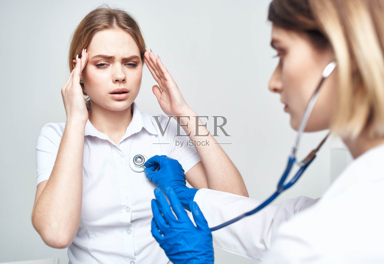 女病人用听诊器向医生抱怨头痛照片摄影图片