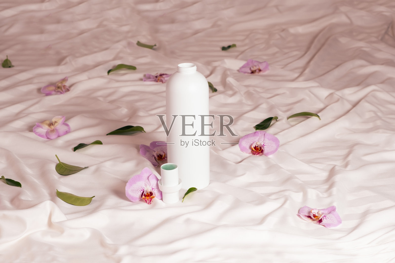 洗涤液或织物柔软剂在床上与兰花花照片摄影图片
