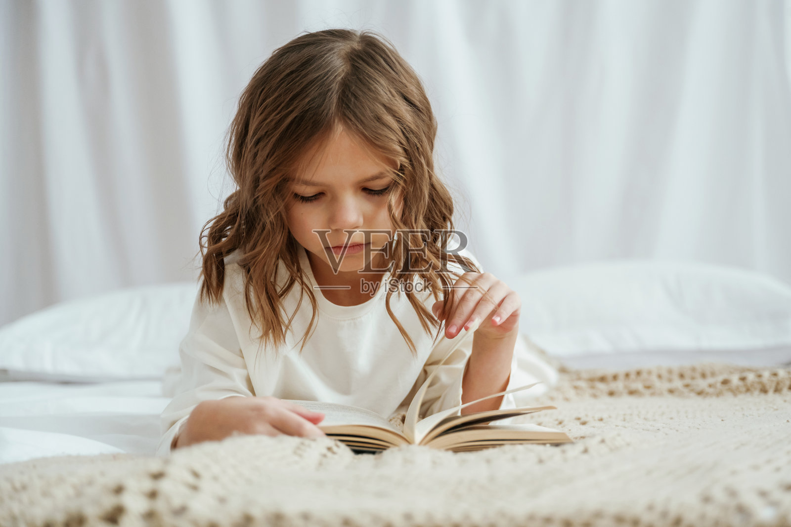 躺在床上看书。可爱的小女孩在家照片摄影图片