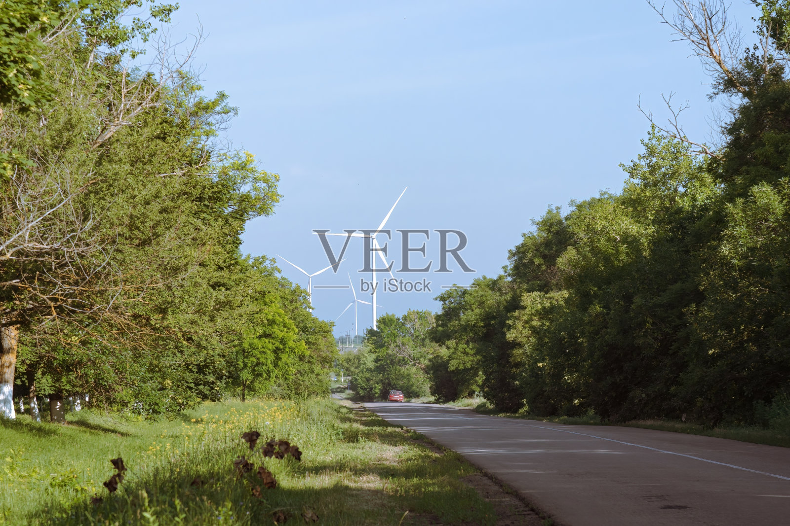 汽车在乡间小路上行驶，对面是有风车的农场照片摄影图片