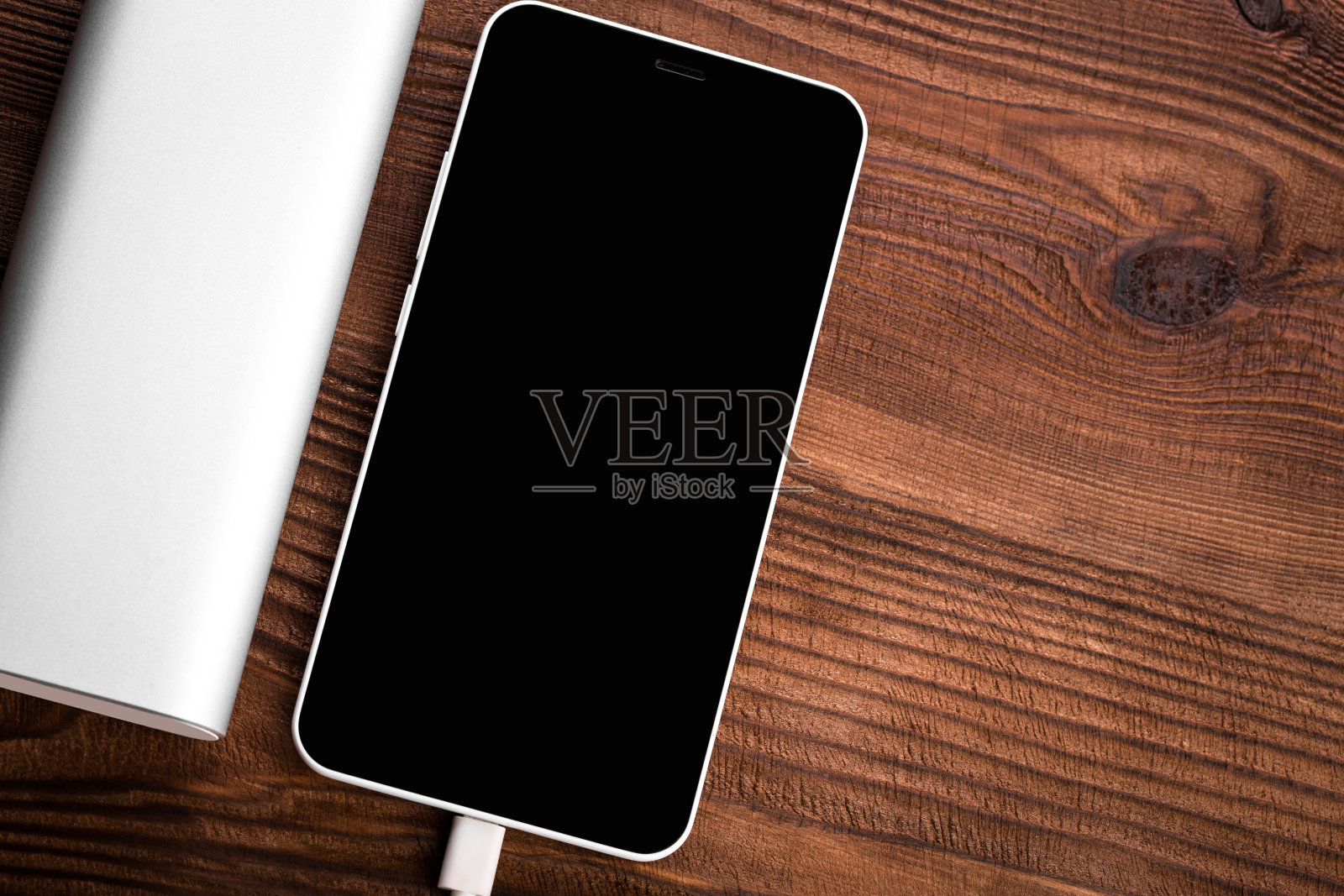 为移动设备充电的充电宝。白色智能手机充电器，带充电宝(电池宝)。移动设备的外置电池。照片摄影图片