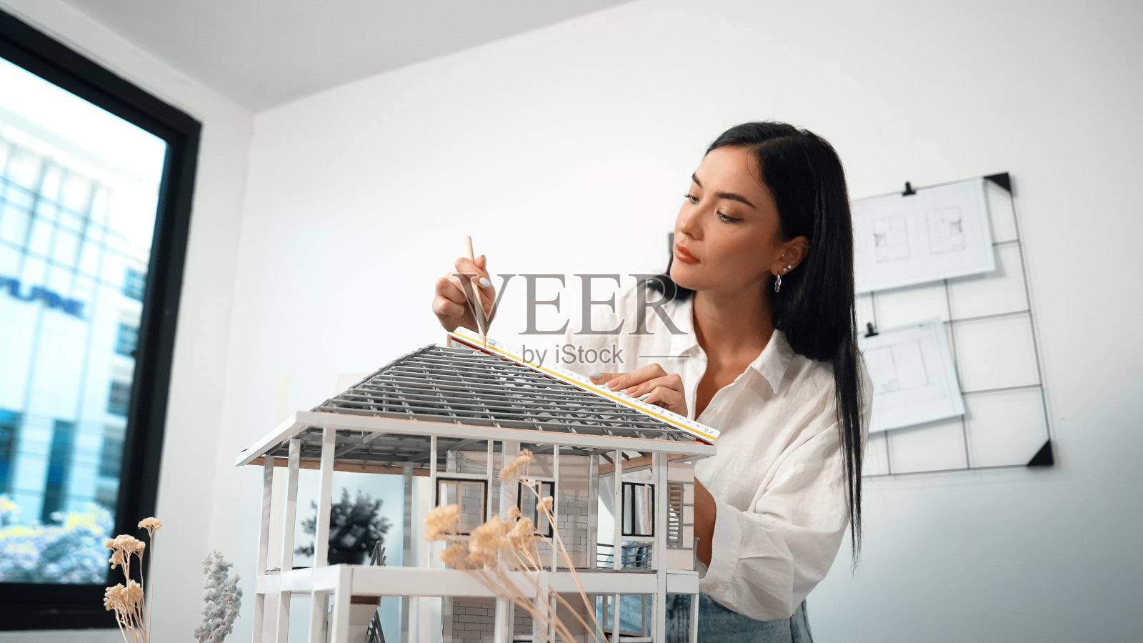 专业建筑师使用尺子测量模型屋顶长度。完美的。照片摄影图片